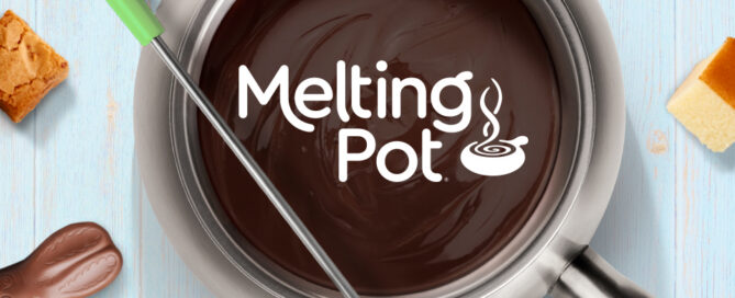A pot of melted chocolate fondue sits on a light blue wooden surface, with the words “Melting Pot” and a steaming bowl logo appearing on the chocolate. A fondue fork with a green handle dips a brownie piece into the chocolate. Around the pot are Easter-themed treats, including chocolate bunnies, decorated eggs, strawberries, and small cubes of cake.